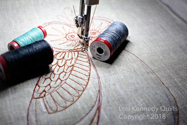 A close up of a sewing machine with three spools of thread