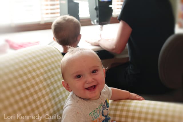 A baby sitting on a couch next to a woman