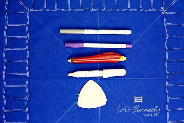 Various pens and sewing markers on top of blue fabric