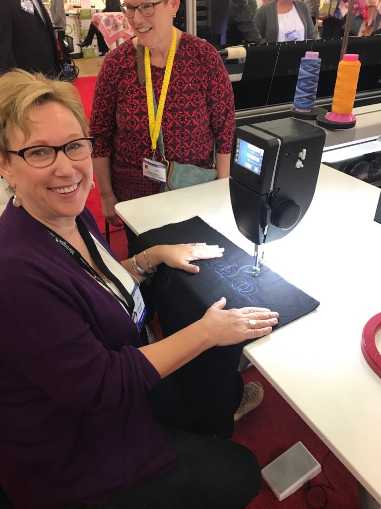 Lori Kennedy working with her quilting machine and woman beside her